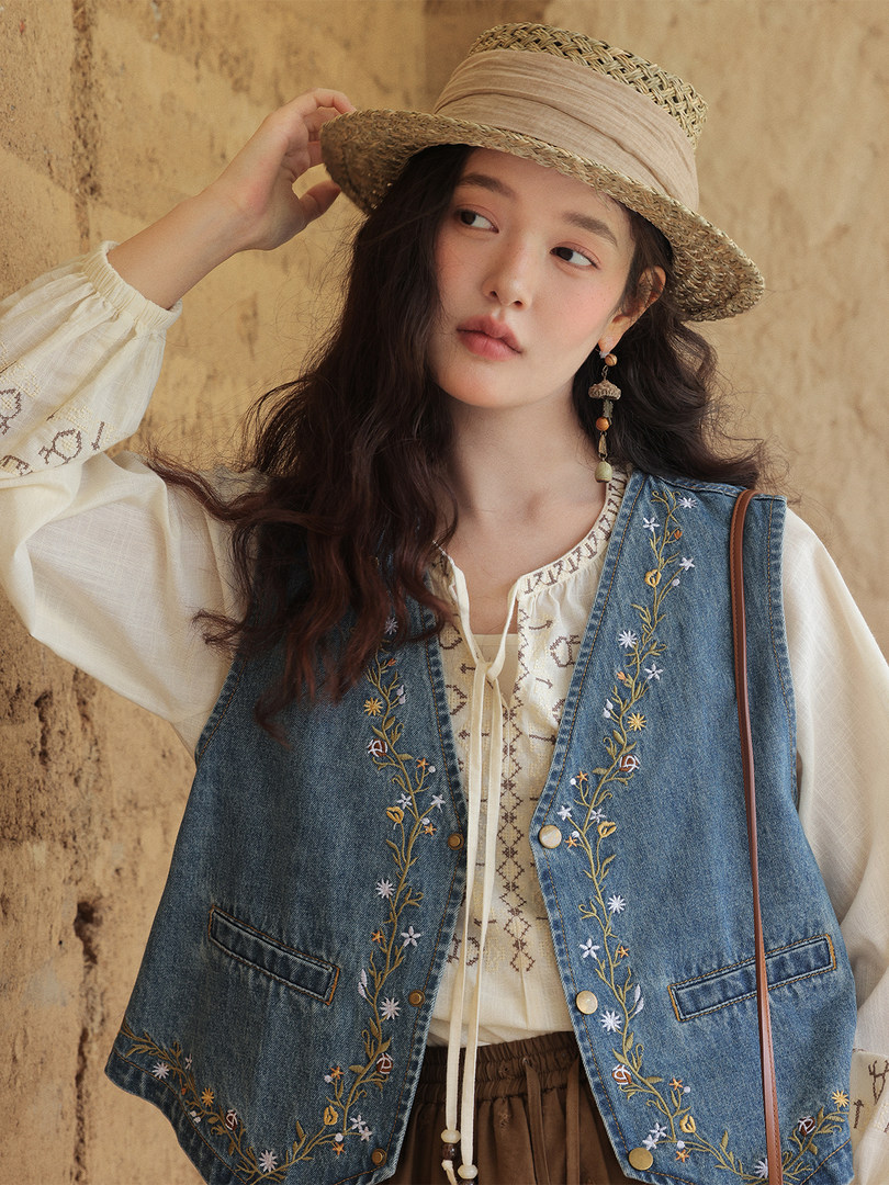 Woman wearing an embroidered denim vest and straw hat