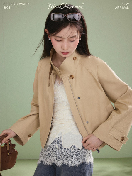Model wearing a beige jacket over a lace top with a brown handbag