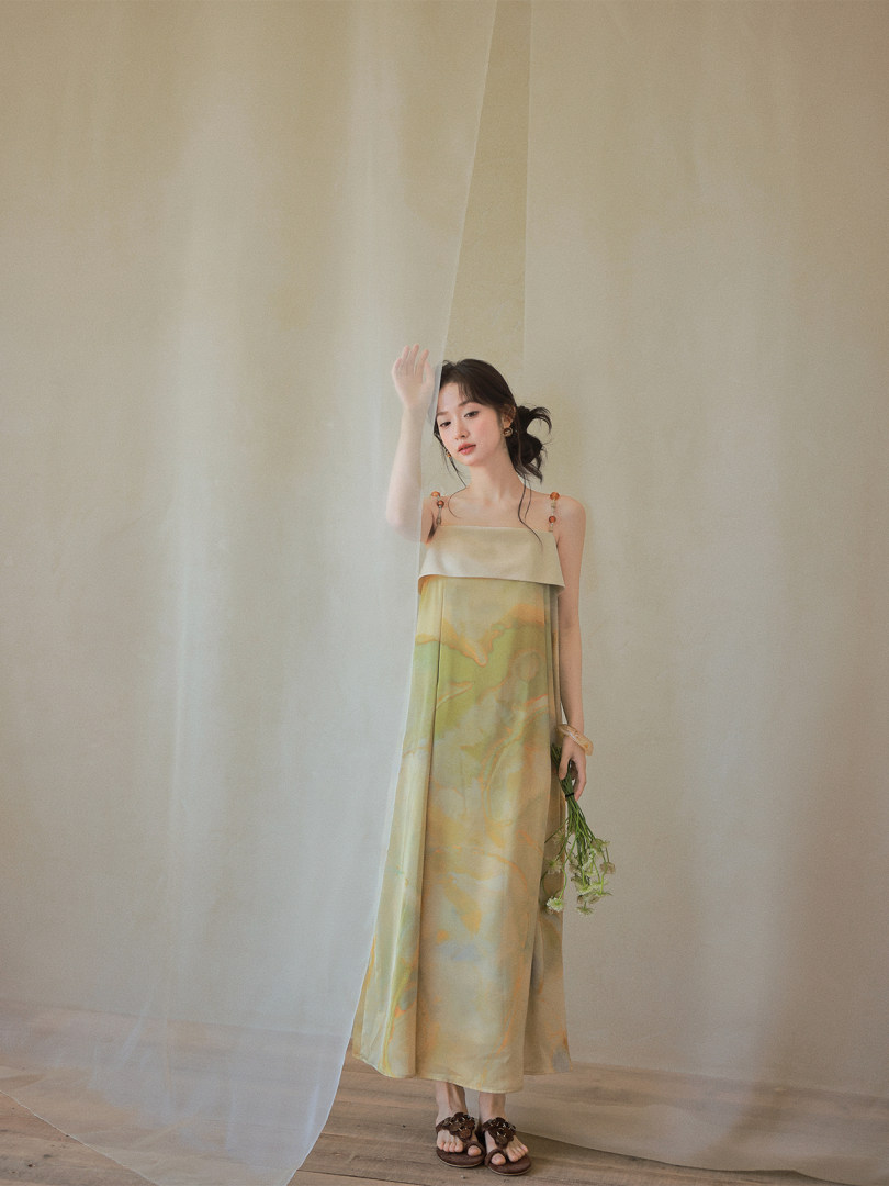 Woman modeling a sleeveless satin dress with a soft floral print
