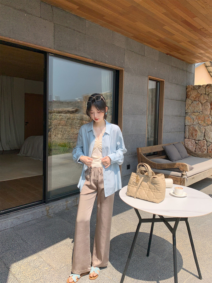 Woman wearing a light blue shirt with beige wide-leg pants outdoors
