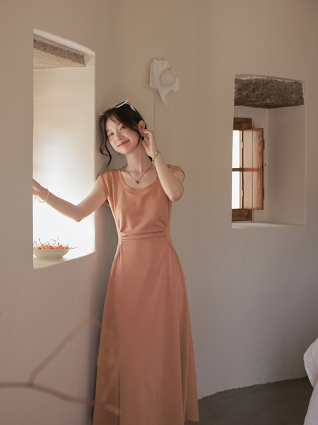 Woman wearing a peach sleeveless long dress indoors