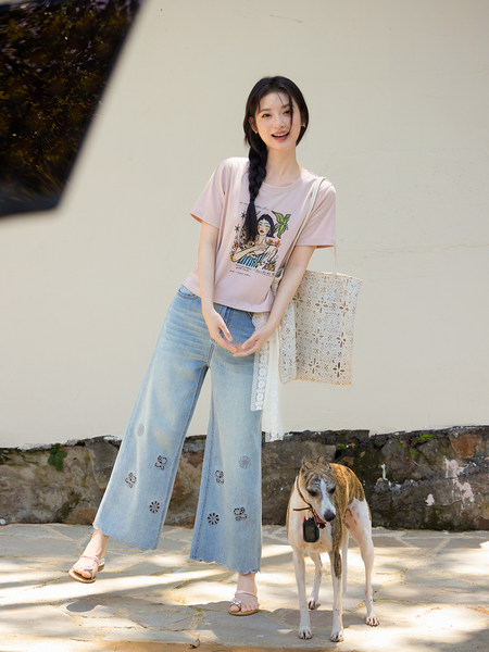 Woman modeling a pink graphic T-shirt with light blue wide-leg jeans outdoors