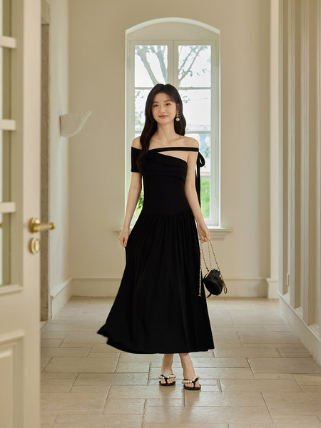 Woman wearing a black off-shoulder midi dress with a handbag