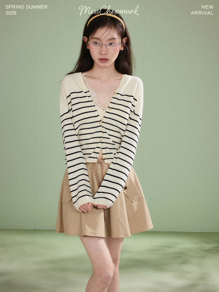 Model wearing a striped cardigan with a beige skirt on a studio background