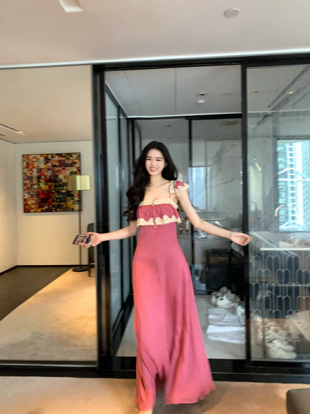 Woman wearing a pink maxi dress with lace trim, posing indoors