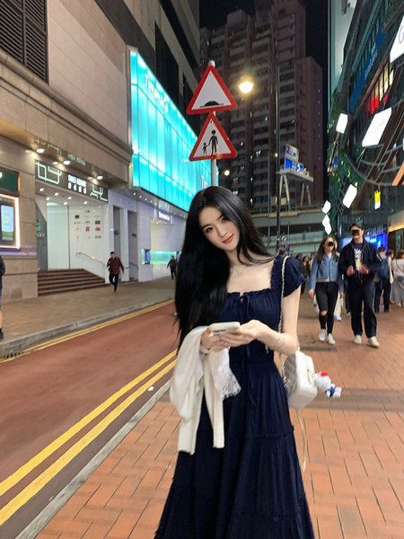 Woman wearing a navy blue dress on a city street at night