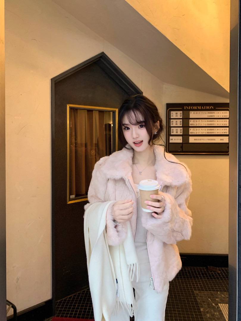 Woman wearing a pink faux fur coat and holding a coffee cup.