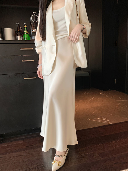 Woman wearing cream satin blazer and matching long skirt with pointed heels