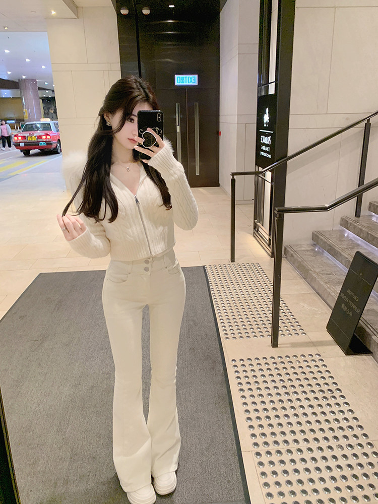 Woman taking mirror selfie wearing white knit zip-up cardigan and matching flared pants in a hotel lobby
