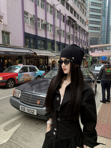 Woman wearing black beanie, sunglasses, and black blazer on city street