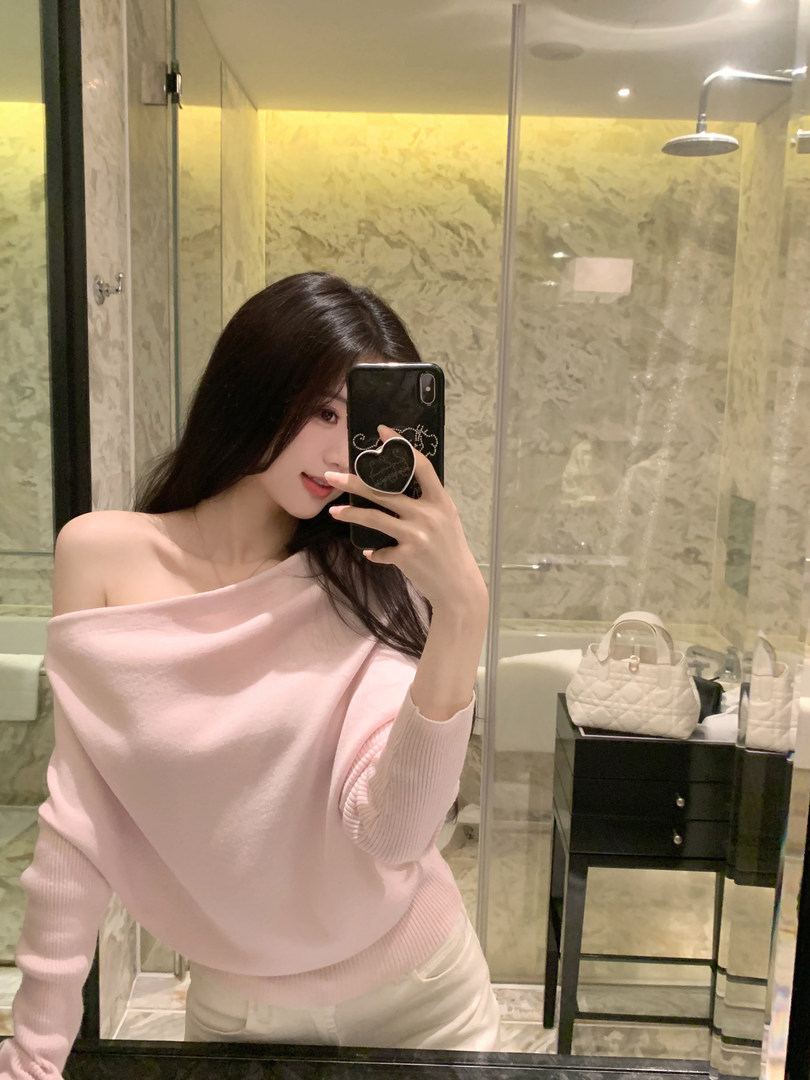 Woman taking mirror selfie wearing pink off-shoulder sweater