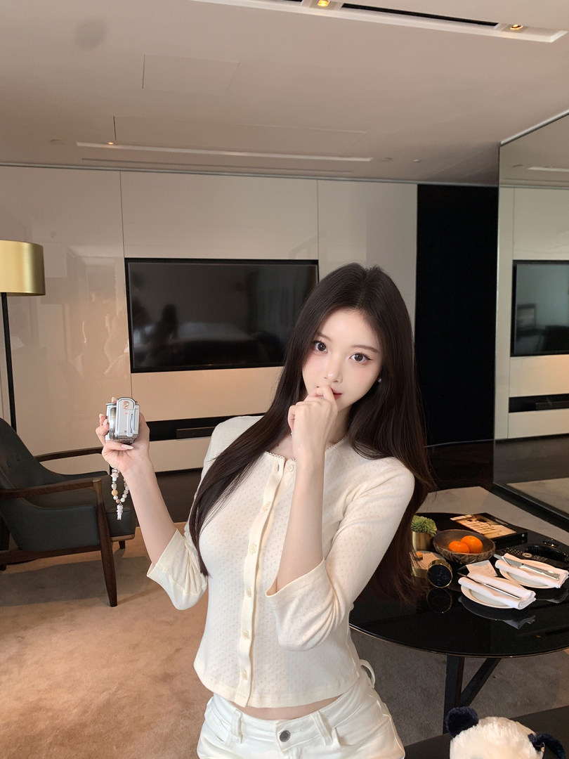 Woman wearing a cream-colored button-up top and matching pants in a modern room