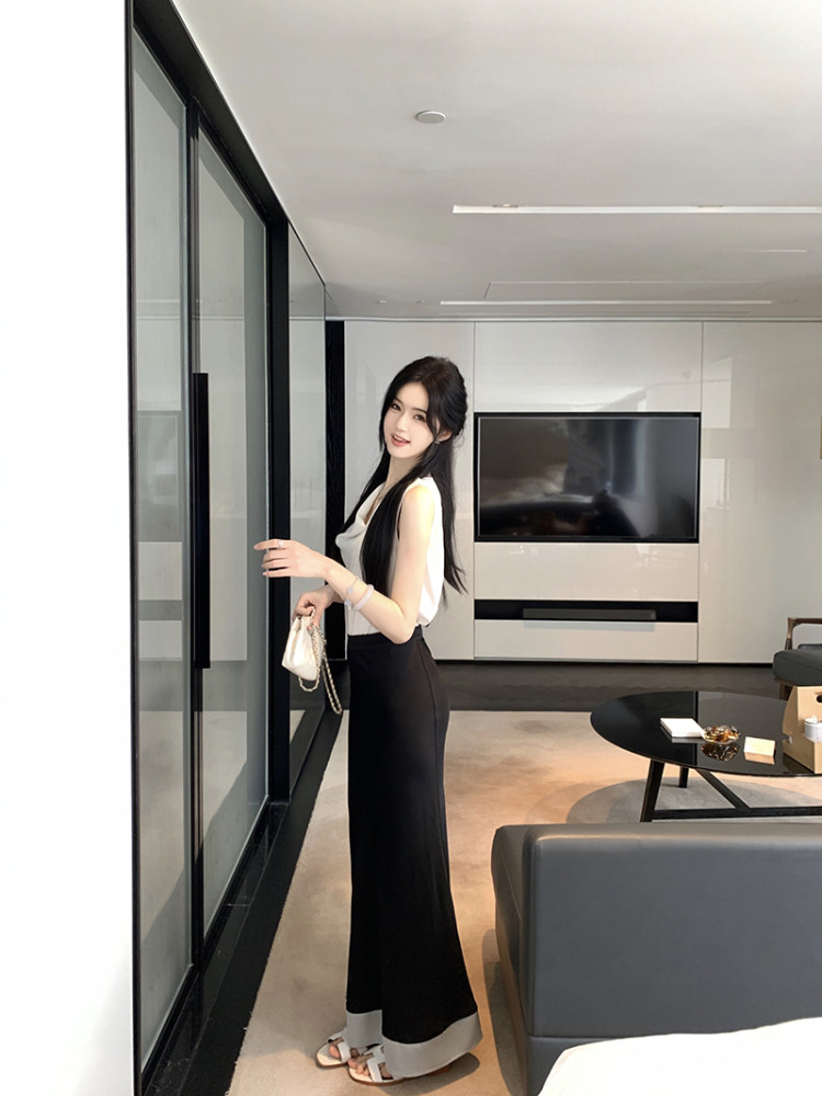 Woman wearing white sleeveless top and black wide-leg pants in a modern living room