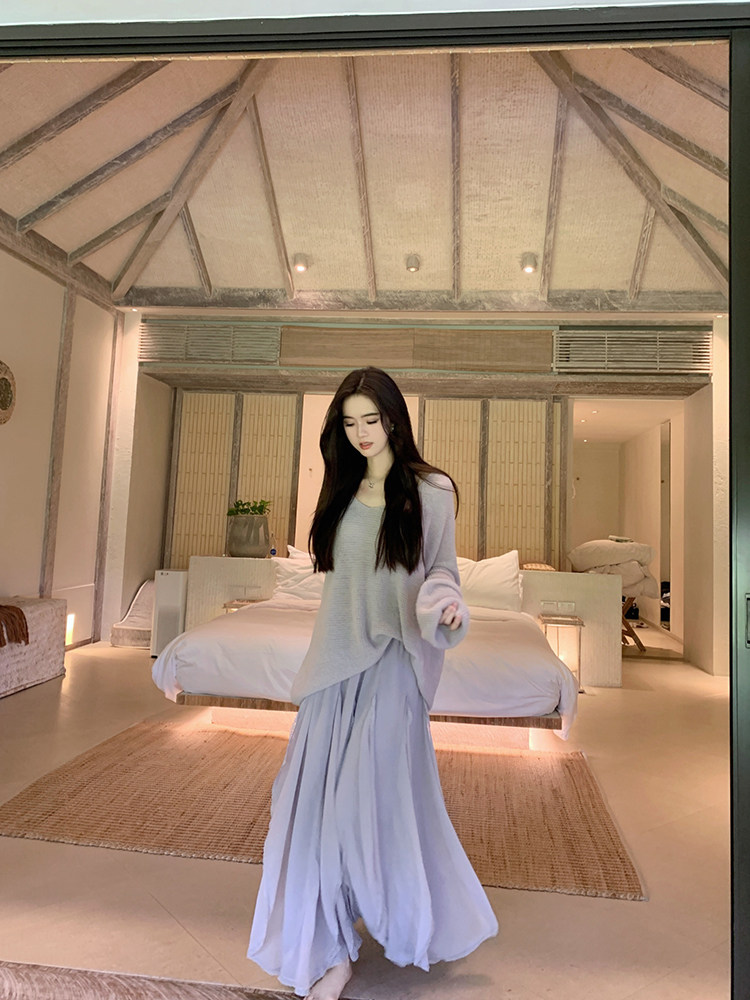 Woman wearing a light purple long skirt and matching cardigan in a modern bedroom setting
