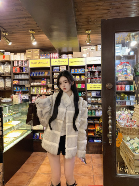 Woman wearing a white faux fur coat in a chocolate shop