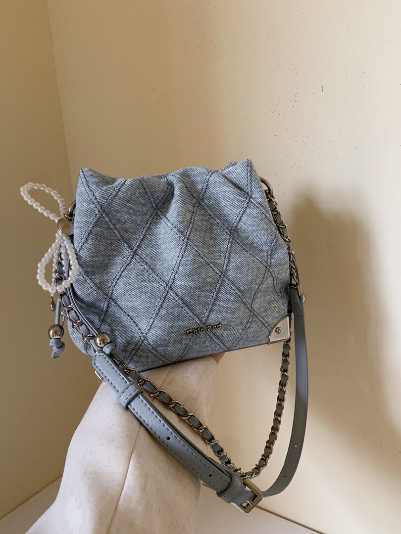 Light blue quilted denim crossbody handbag with chain strap and pearl charm