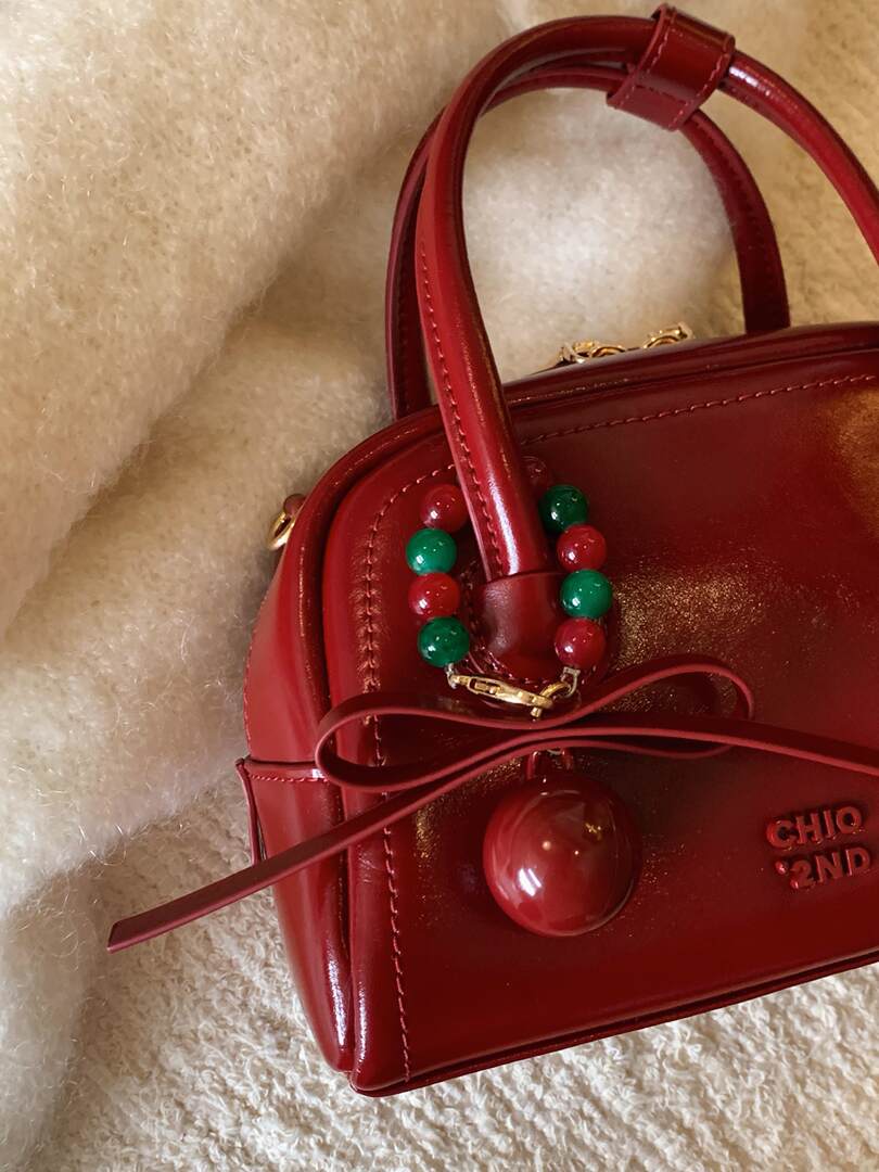 Red glossy structured handbag with red and green beaded charm