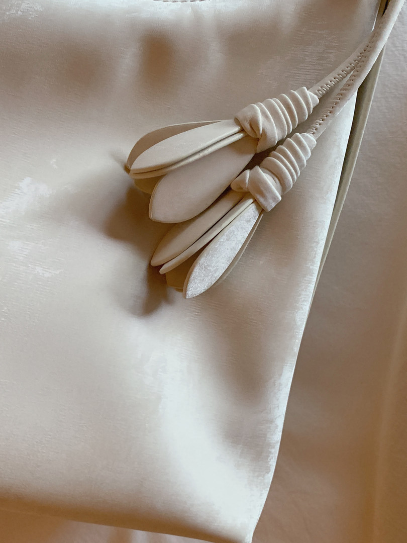 Close-up of a white satin garment with a decorative tie detail