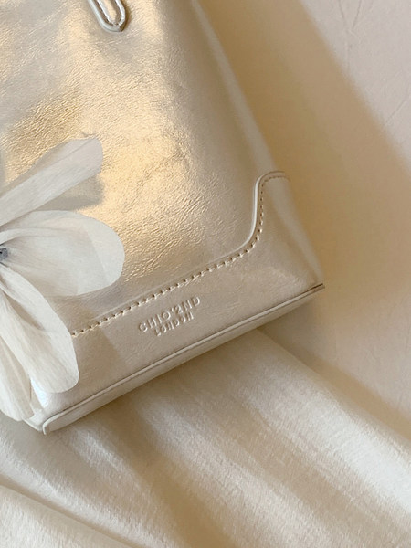 Beige leather handbag with floral detail and brand logo