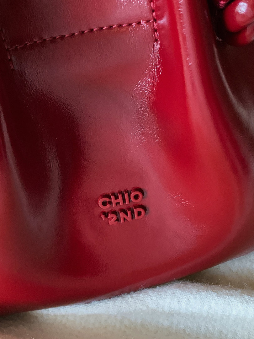 Close-up of a glossy red leather accessory with embossed branding