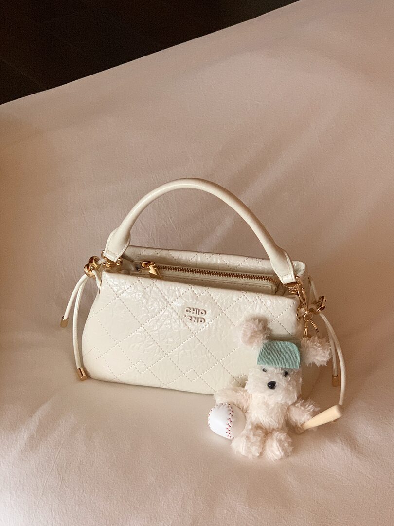 White quilted handbag with top handle and teddy bear charm