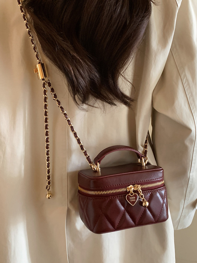 Brown quilted mini handbag with gold chain strap worn crossbody