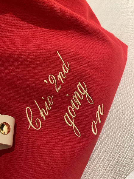 Close-up of a red embroidered fabric clutch or bag with gold hardware