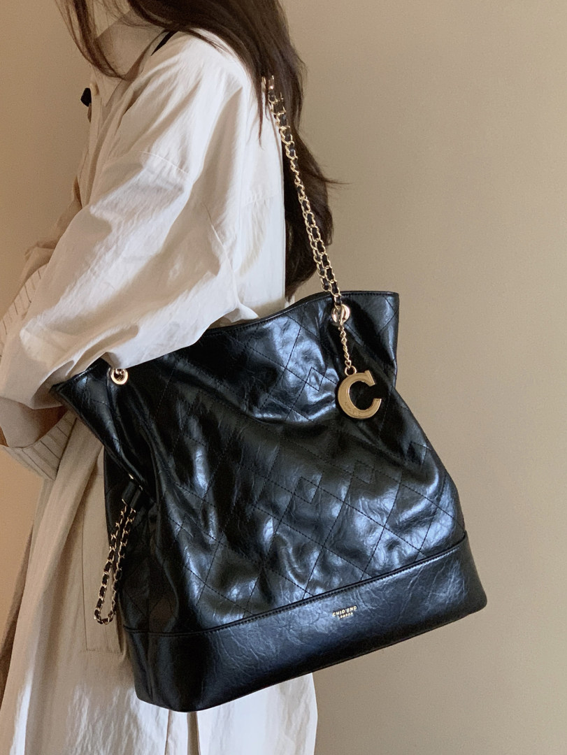 Black quilted leather chain-strap tote bag worn on a model