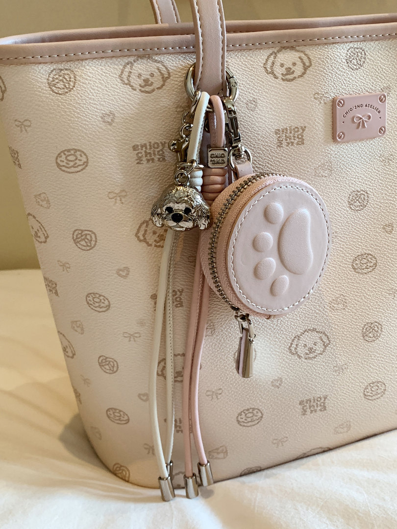 Light pink designer tote bag with paw-print pattern and hanging charm accessories