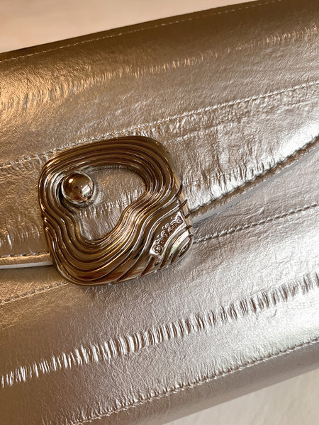 Close-up of a metallic gold clutch handbag with decorative clasp