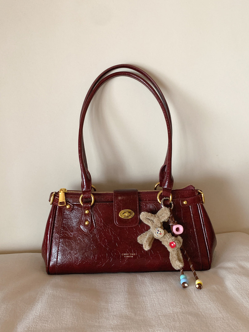 Burgundy leather handbag with gold hardware and charm