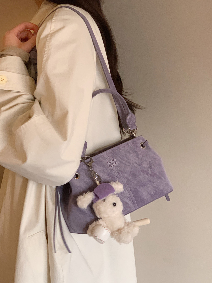 Lavender shoulder bag with teddy charm worn by a model