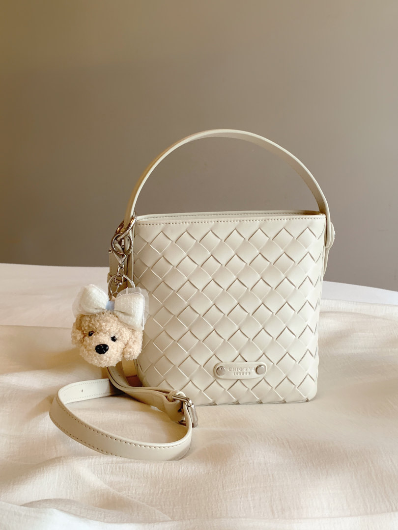 Cream woven bucket handbag with shoulder strap and bear charm