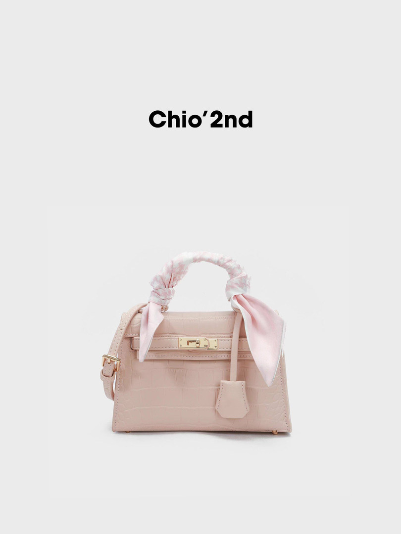 Light pink structured handbag with scarf-wrapped handle on a white background