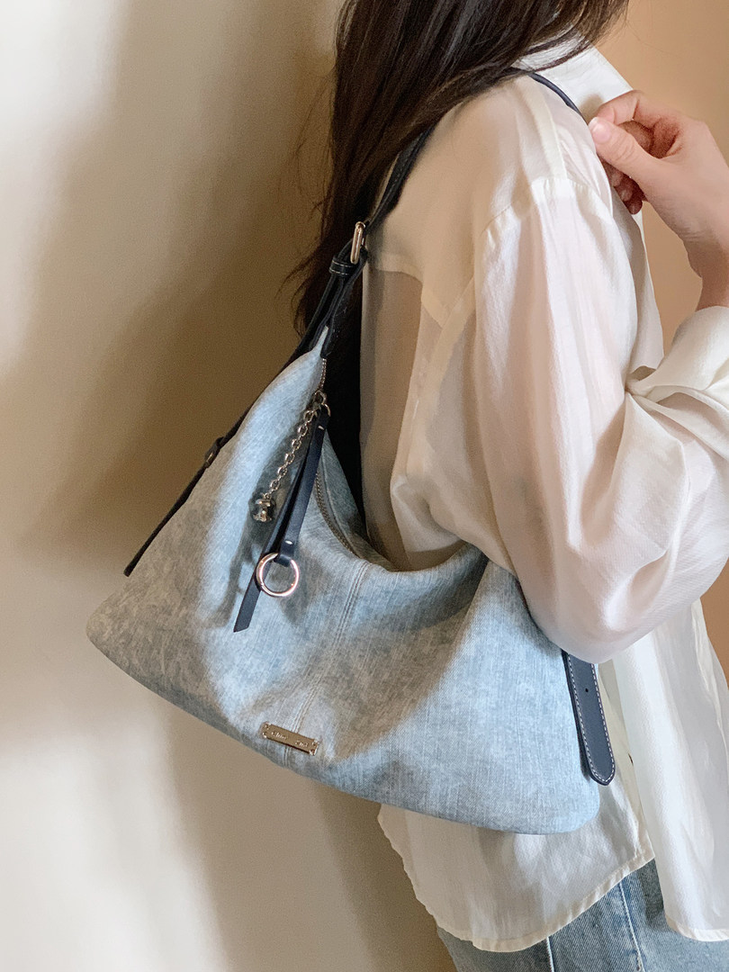 Light blue denim shoulder bag worn over a white blouse
