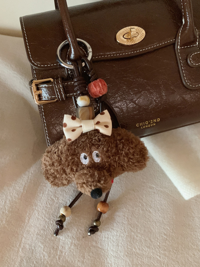 Brown leather handbag with a teddy bear charm