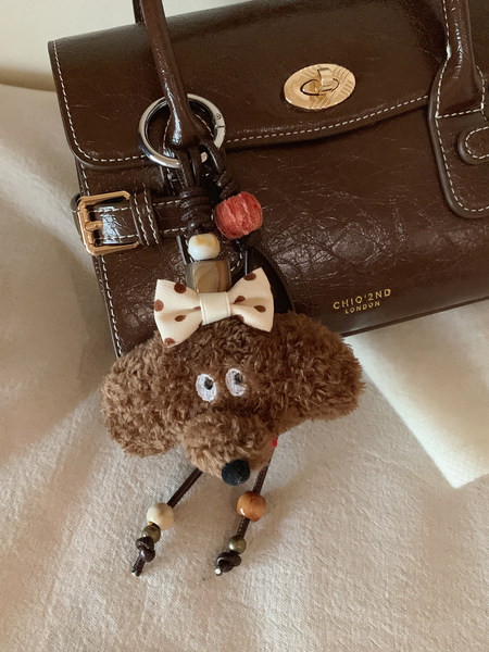 Brown leather handbag with a teddy bear charm