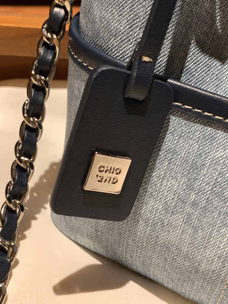 Close-up of a blue and black leather handbag with chain strap and metal logo detail