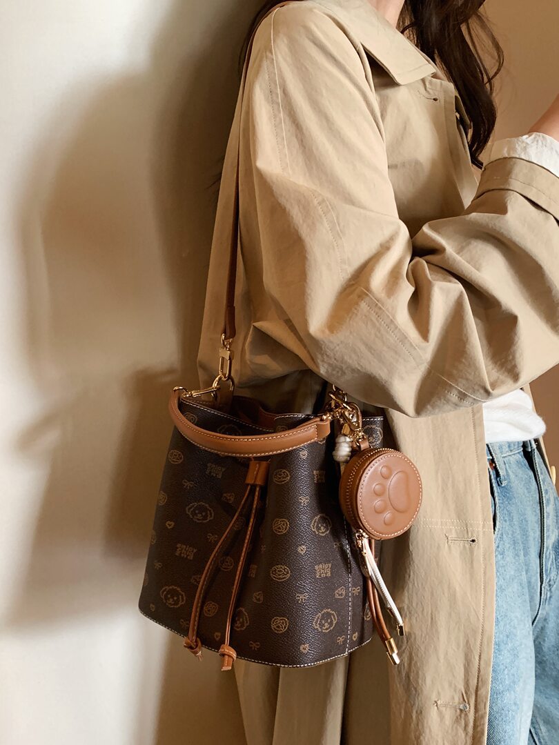 Brown monogram bucket handbag worn crossbody on a model