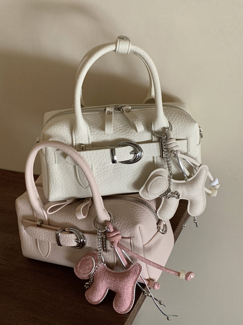 Two pastel leather handbags with decorative charms on a table