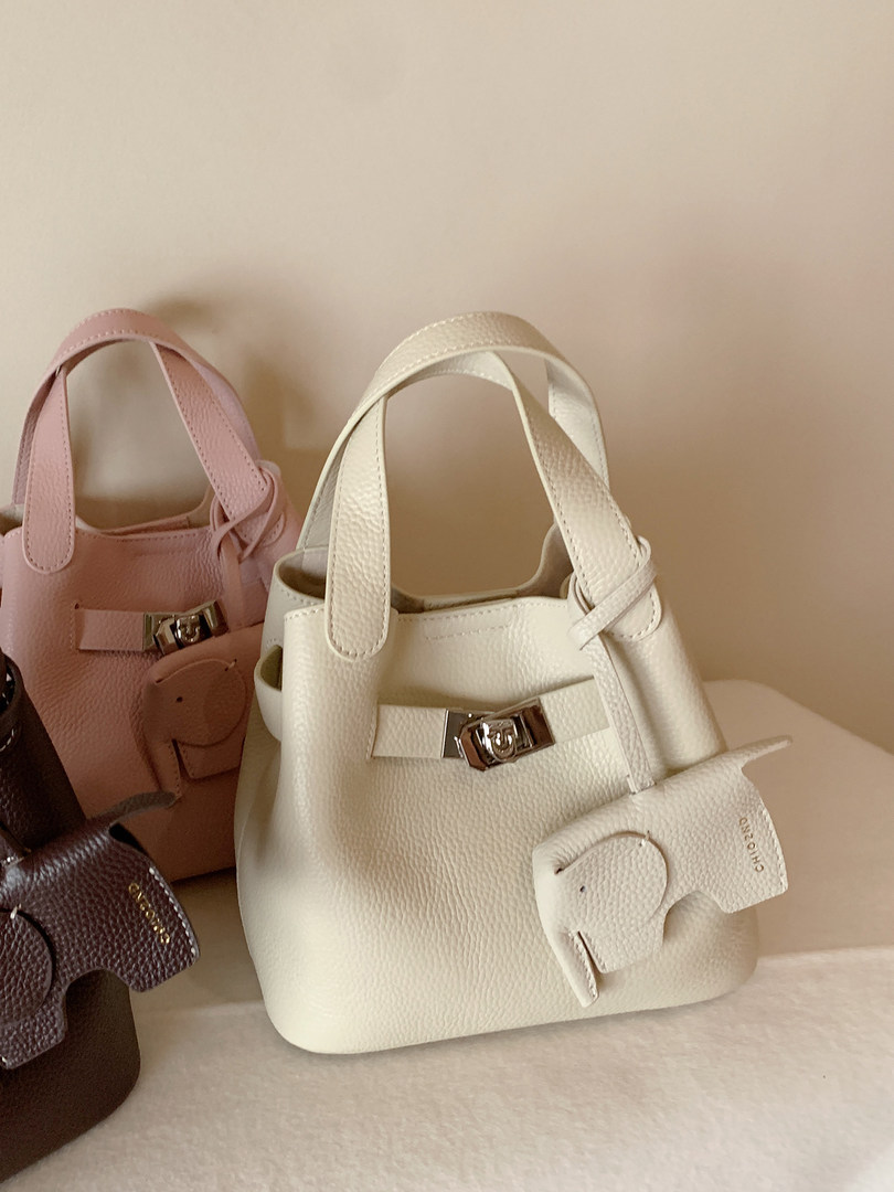 Textured mini handbags in white, pink, brown, and purple with buckle details