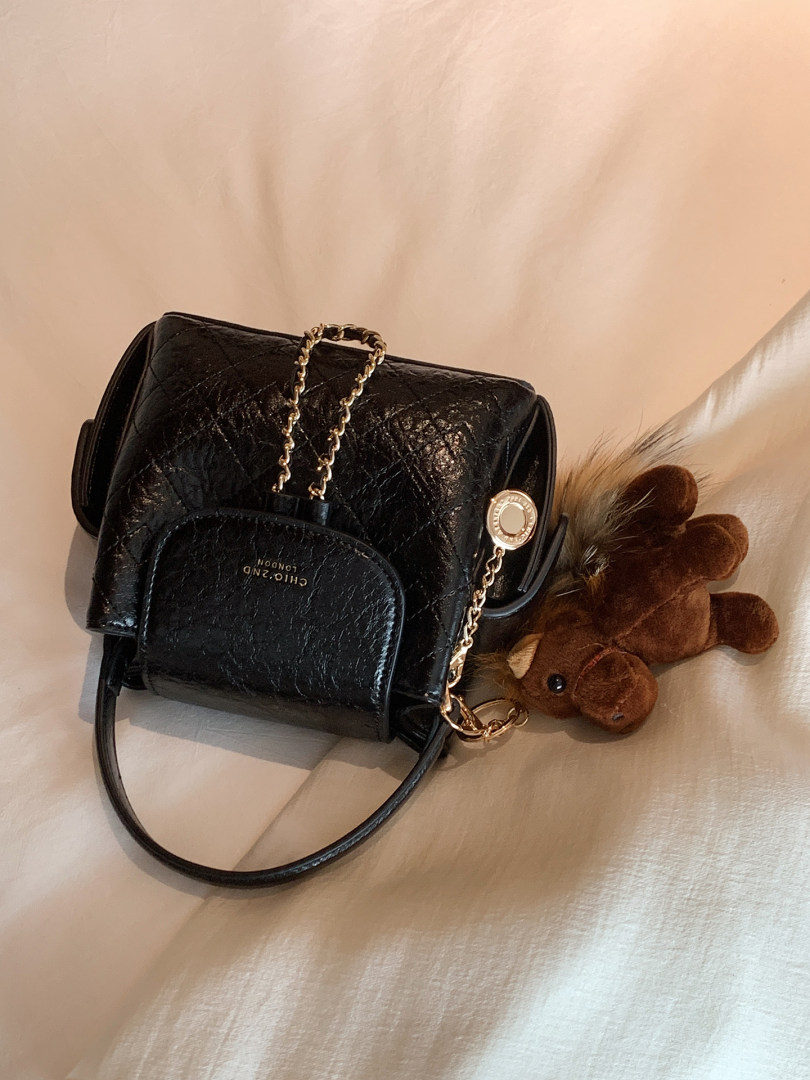 Black quilted leather handbag with gold chain and teddy charm