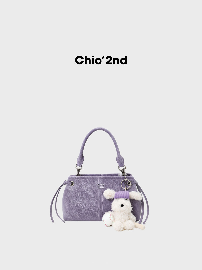 Lavender handbag with a plush teddy charm on a white background