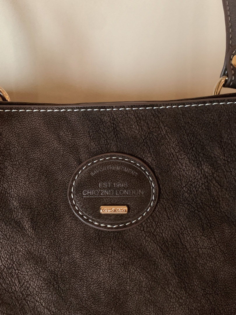 Close-up of a dark brown leather handbag with embossed brand logo
