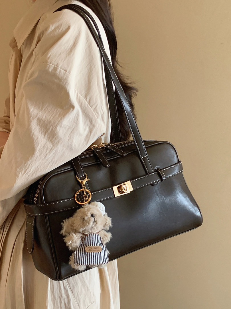 Black leather handbag worn on shoulder with teddy bear charm