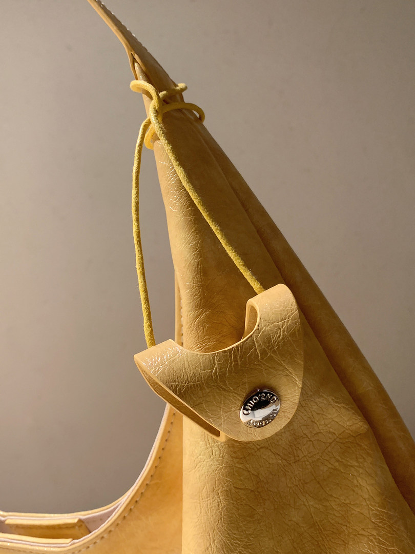 Close-up of a yellow leather handbag with drawstring detail