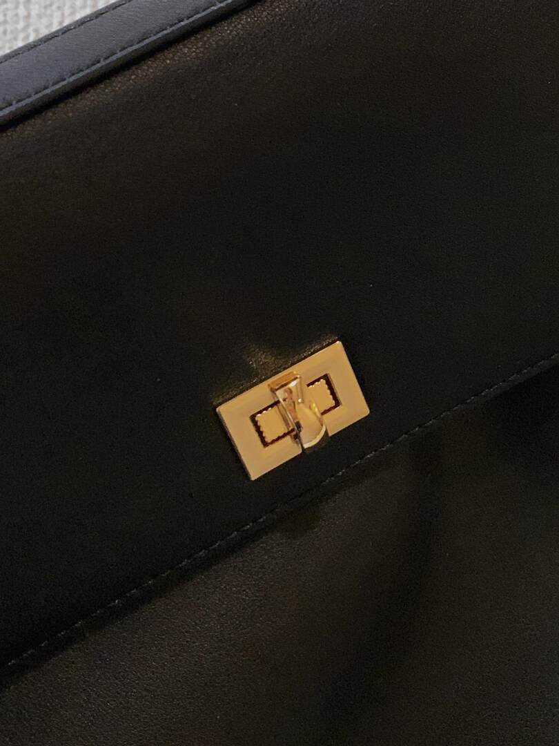Close-up of a black leather handbag with a gold clasp