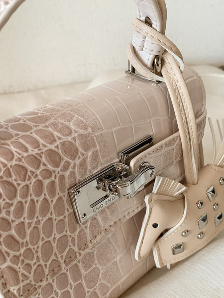 Beige crocodile-textured handbag with metal clasp and strap detail