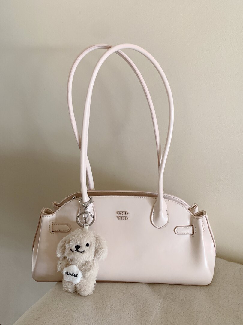 Light pink handbag with long handles and a plush teddy charm