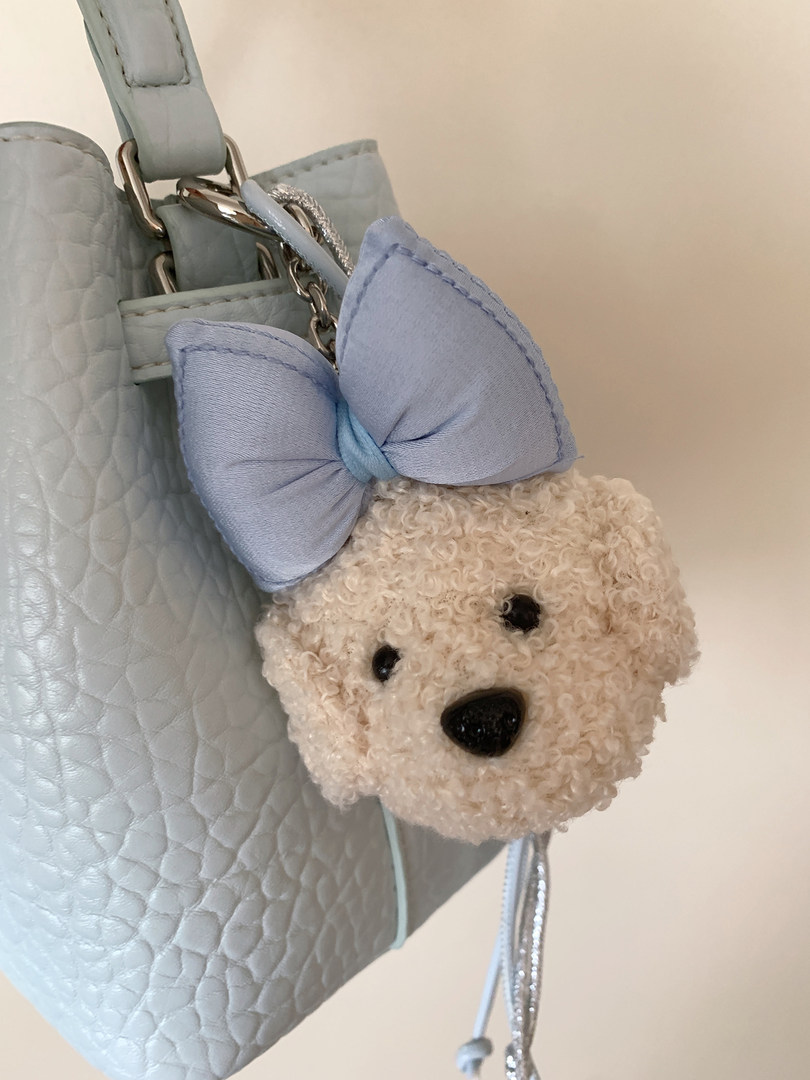Light blue quilted handbag with a teddy bear charm and bow accessory